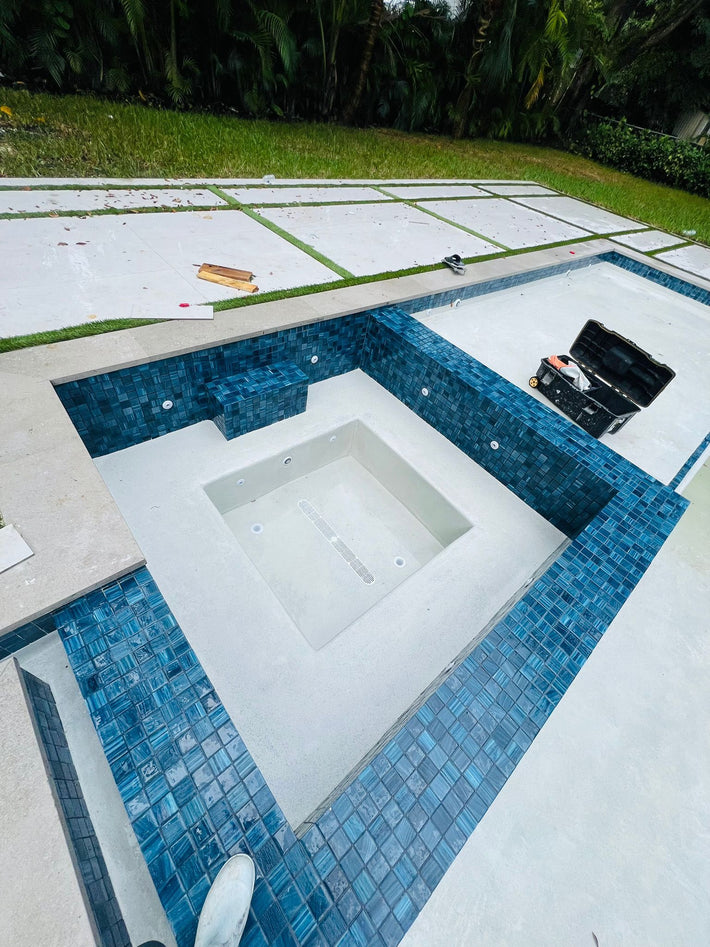 Professional contractors installing coping and waterline tiles in Miami pools